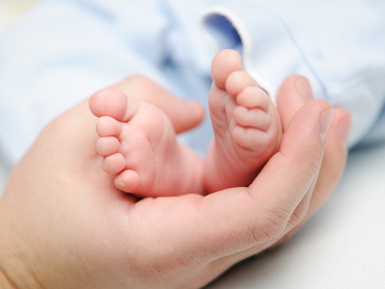 En hand håller fötterna på en nyfödd