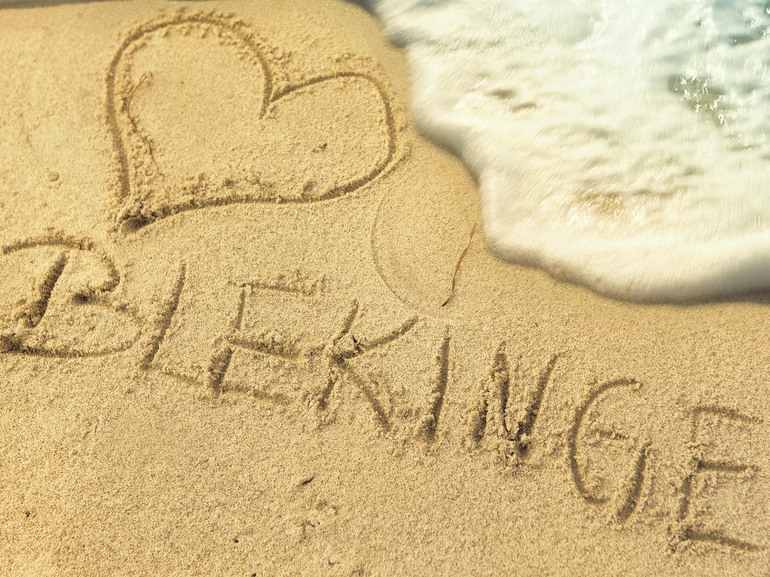 Hjärta och "Blekinge" skrivet i sand på en strand.
