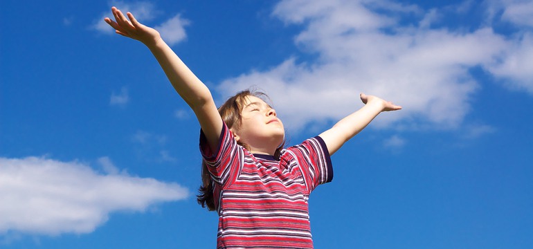 Bild på en flicka som håller upp händerna mot himmelen