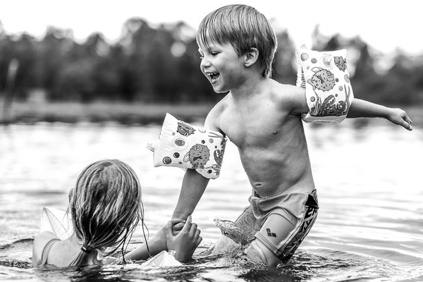 Två barn som badar i en sjö