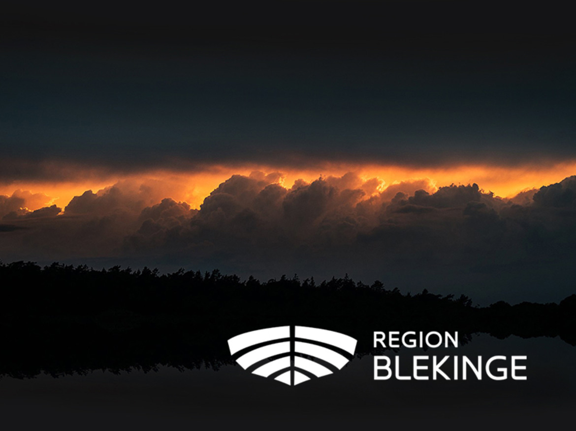 En skog i mörker med solnedgången i bakgrunden och Region Blekinges vita logotyp i förgrunden.