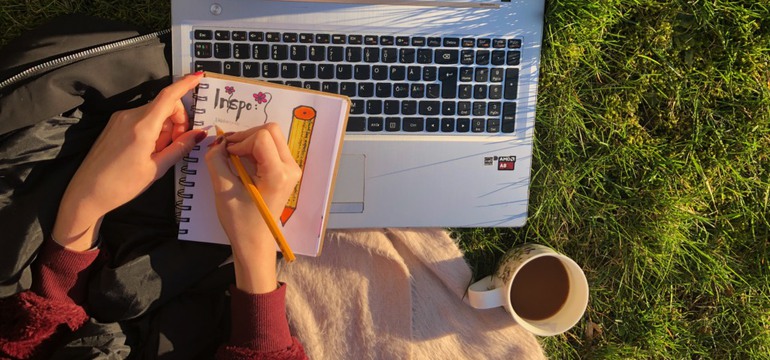 Bild av två händer som antecknar. Man ser bara händer, penna, papper, dator, en kopp kaffe, gräset på marken och ordet "Inspo".