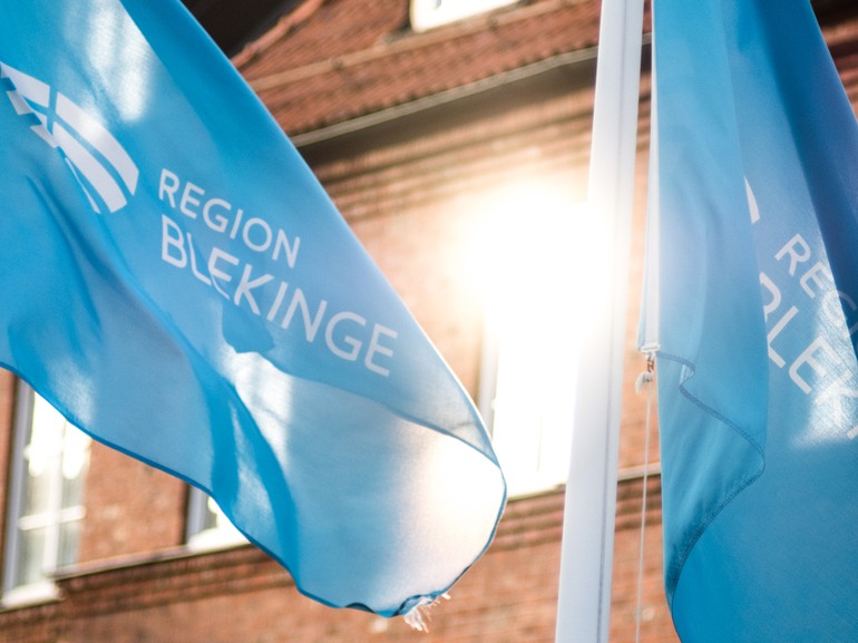 En närbild på blåa flaggor med Region Blekinges logotyp.