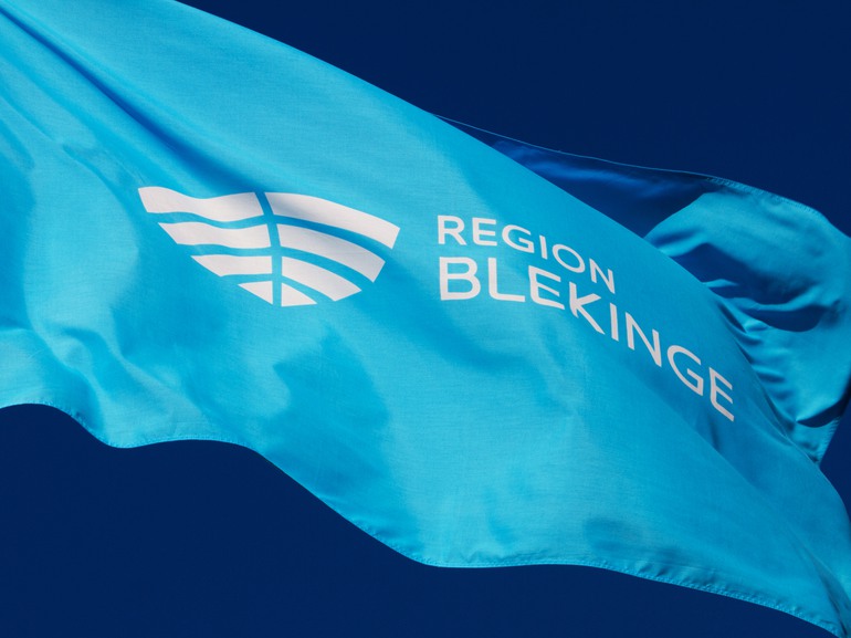 Region Blekinges logotyp mot en klarblå himmel.