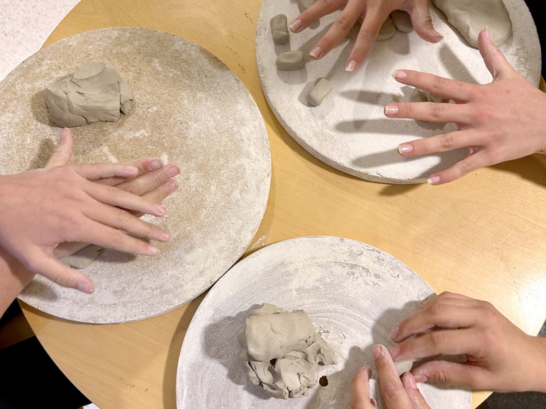 Bild på händer som arbetar med lera. 