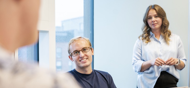 En man och kvinna som tittar på en person som syns suddigt i förgrunden 