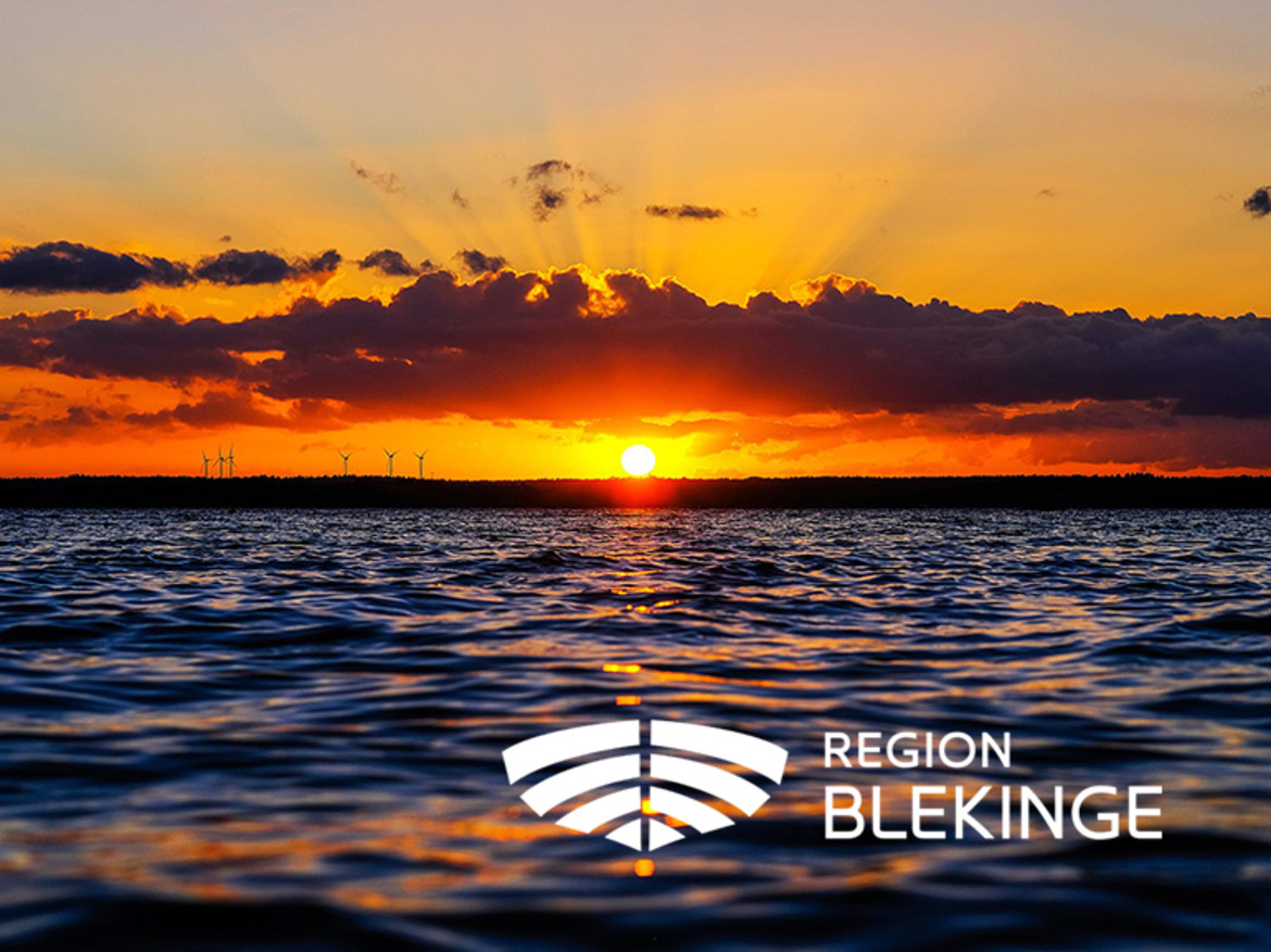 Solnedgång vid vattnet och Region Blekinges vita logotyp i förgrunden.