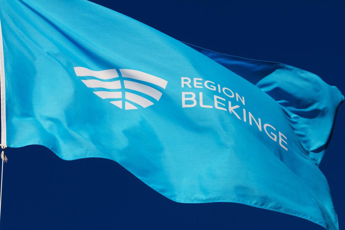 Blå flagga med Region Blekinges vita logotyp.