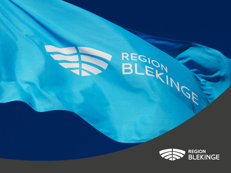 Närbild på en blå flagga med Region Blekinges logotyp på.