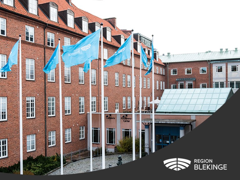 Region Blekinges logotyp med bild på ingången till Wämö center samt Region Blekinges flaggor