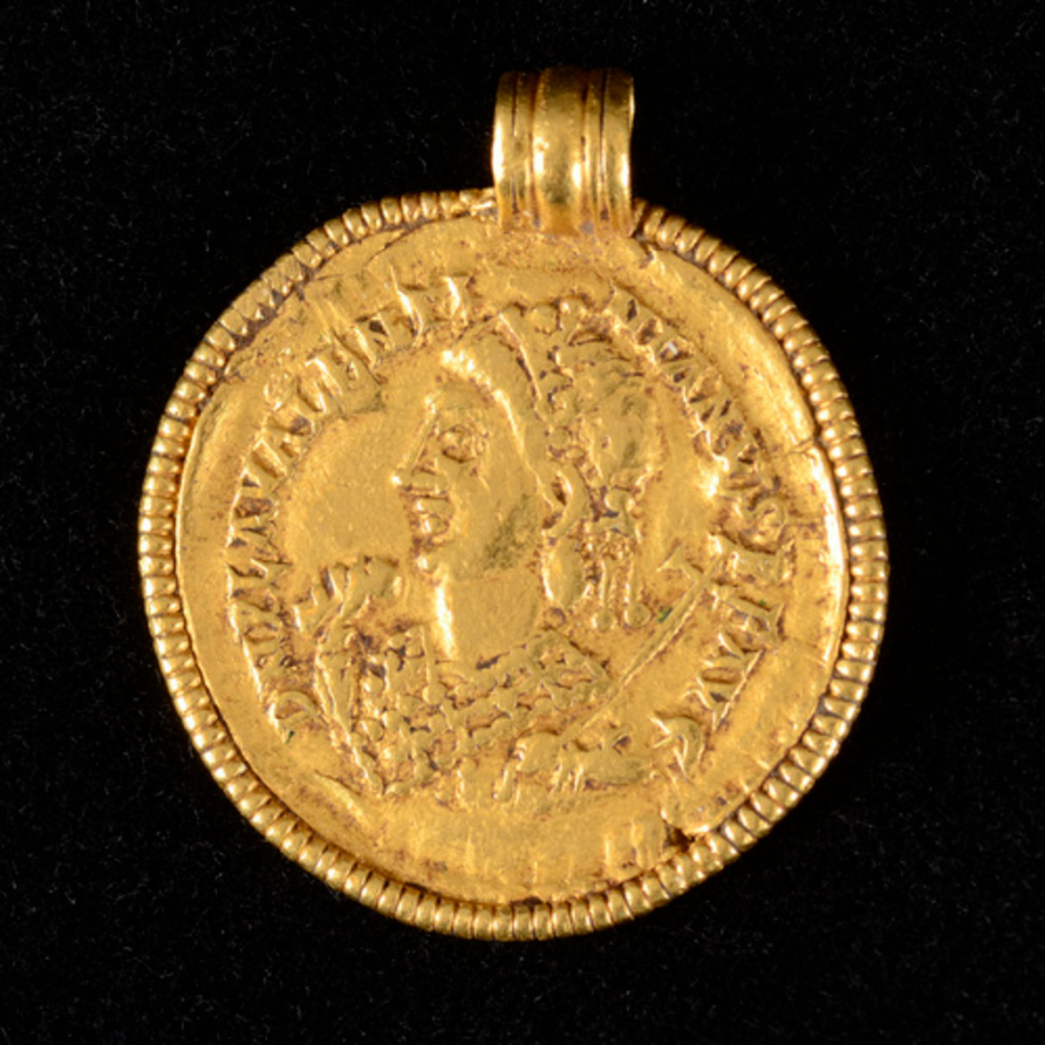 Ett guldmynt med hängögla. En person i profil syns på myntet.