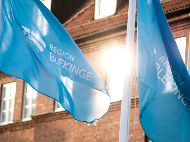 En närbild på blåa flaggor med Region Blekinges logotyp.