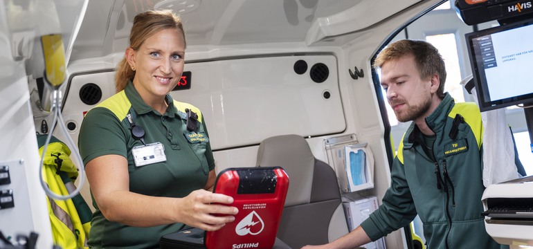 Två specialistsjuksköterskor förbereder ambulansen inför en utryckning. 