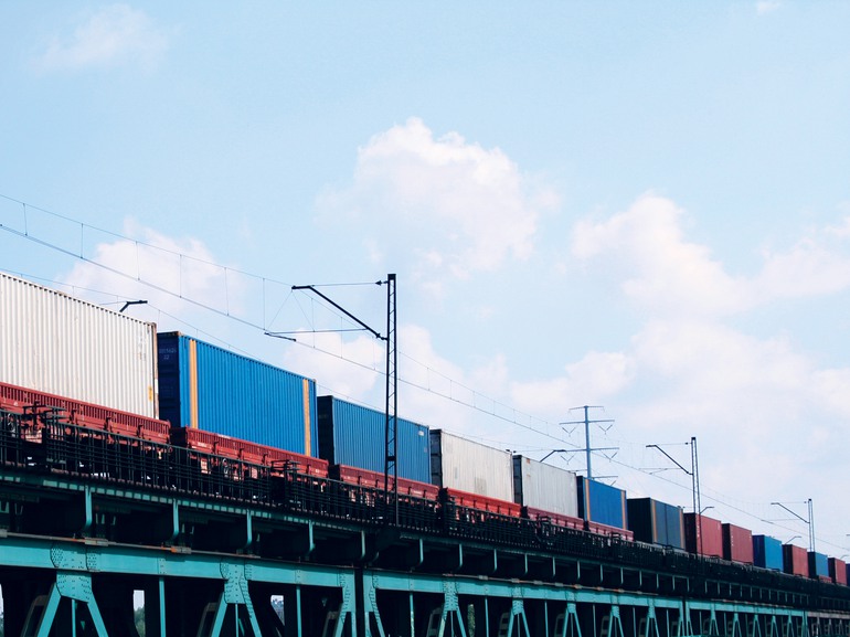Godståg med containrar i olika färger på en järnvägsbro